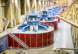 Row of hydropower generators at a dam. The huge turbines in these generators turn as the water blasts through, creating electricity